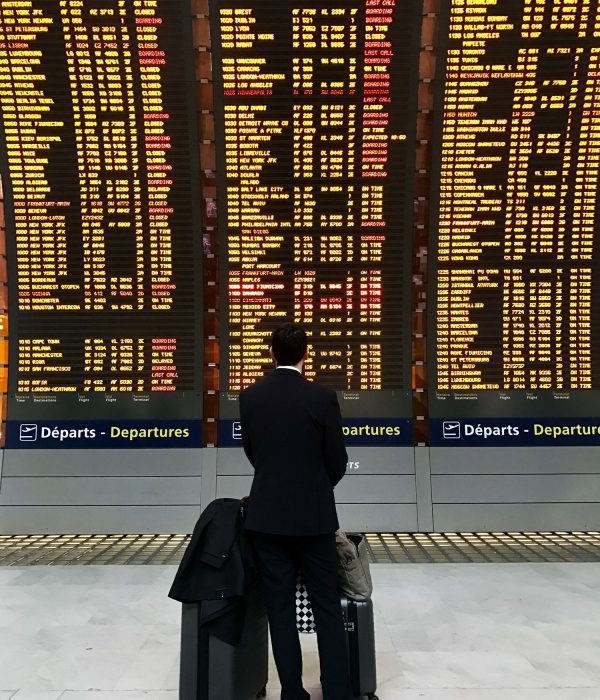 Businessman with a briefcase on a background of departure board at airport